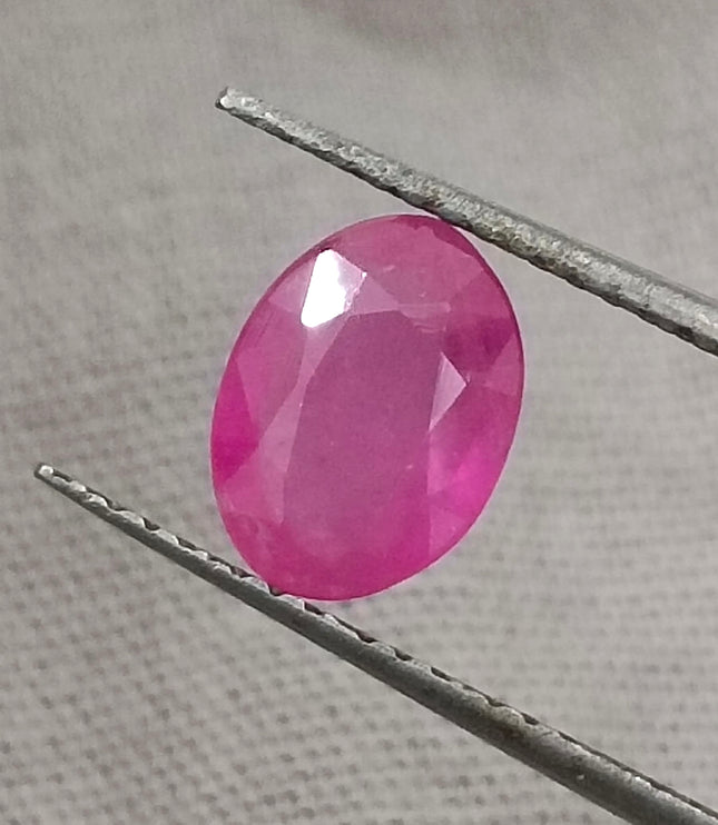 GSI Certified 1.31ct natural untreated pinkish red African ruby gemstone held with tweezers.