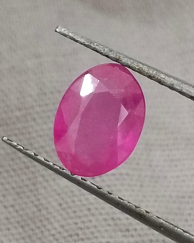 GSI Certified 1.31ct natural untreated pinkish red African ruby gemstone held with tweezers.