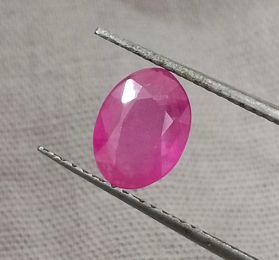 GSI Certified 1.31ct natural untreated pinkish red African ruby gemstone held with tweezers.
